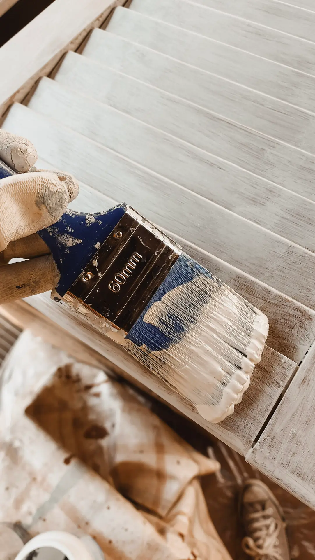 Close-up of a brush painting wooden shutters during the restoration of Casa Mafalda